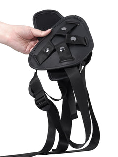 Adjustable black strap-on harness held in hand to show the straps